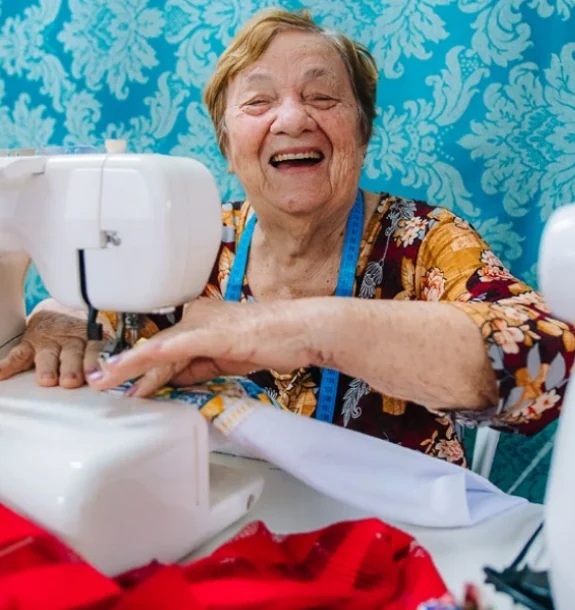 Professora Daniela sorrindo enquanto costura